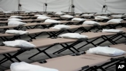 Bolsas con una almohada, toalla y sábanas están colocadas en catres al interior de una carpa dormitorio durante una gira de prensa a un albergue que la ciudad de Nueva York está montando para albergar hasta 1.000 migrantes en el barrio de Queens, el 5 de agosto de 2023. 