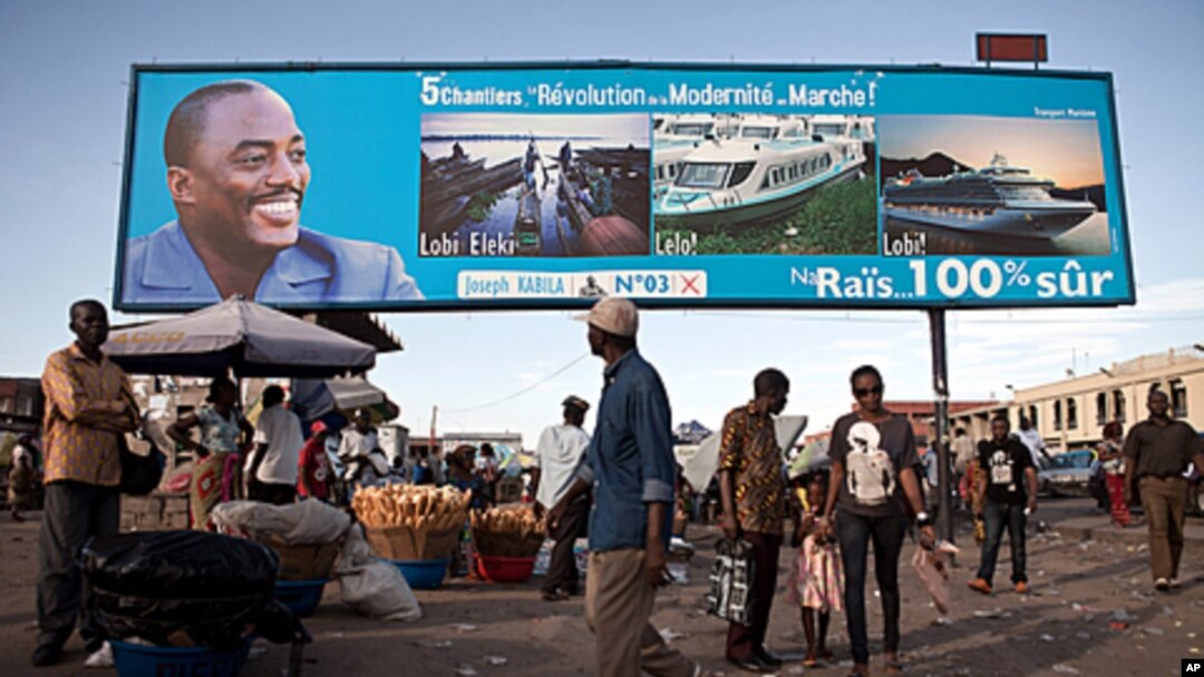 FILE - People walk under a giant poster showing Democratic Republic of the Congo's President and candidate for a second term Joseph Kabila, in Kinshasa, Nov. 7, 2011.