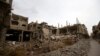 Posters of Syria's President Bashal al-Assad hang on a building in the central Syrian town of al-Qaryatain in the Homs province, Dec. 20, 2021, next to buildings damaged during fbattles in 2015 between the Islamic State group (IS) and government forces. 