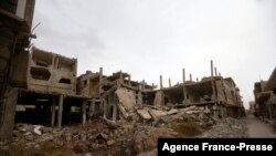 Posters of Syria's President Bashal al-Assad hang on a building in the central Syrian town of al-Qaryatain in the Homs province, Dec. 20, 2021, next to buildings damaged during fbattles in 2015 between the Islamic State group (IS) and government forces. 