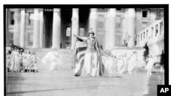 In this photo provided by the Library of Congress, taken in 1913, German actress Hedwig Reicher wearing costume of "Columbia" with other suffrage pageant participants standing in background in front of the Treasury Building in Washington. 