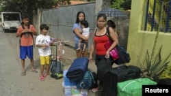 Residents wait for a truck to transport them into an evacuation center as local officials ordered enforced evacuation ahead of Typhoon Bopha in Cagayan de Oro City, southern Philippines, December 3, 2012.