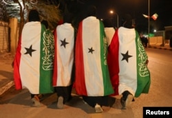 Members of the Hargeisa Basketball Girls team wrapped in the Somaliland flags walk on Road Number One during the Independence Day Eve celebrations in Hargeisa, Somaliland, May 17, 2024. (REUTERS/Tiksa Negeri)