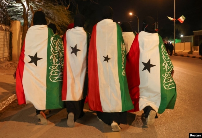 Members of the Hargeisa Basketball Girls team wrapped in the Somaliland flags walk on Road Number One during the Independence Day Eve celebrations in Hargeisa, Somaliland, May 17, 2024. (REUTERS/Tiksa Negeri)