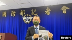 台湾国防部官员2023年6月13日展示最新版民防手册。（路透社）