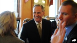 File Photo - South Dakota Gov. Dennis Daugaard greets Secretary of State Shantel Krebs, left, shortly before giving his State of the State address to the South Dakota Legislature, Tuesday, Jan. 12, 2016, at the state Capitol in Pierre, S.D. (AP Photo/James Nord)