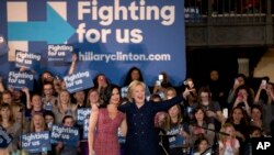 Democratic presidential candidate Hillary Clinton and musician Demi Lovato acknowledge the cheering crowd at a rally on the campus of University of Iowa in Iowa City, Iowa, Jan. 21, 2016.