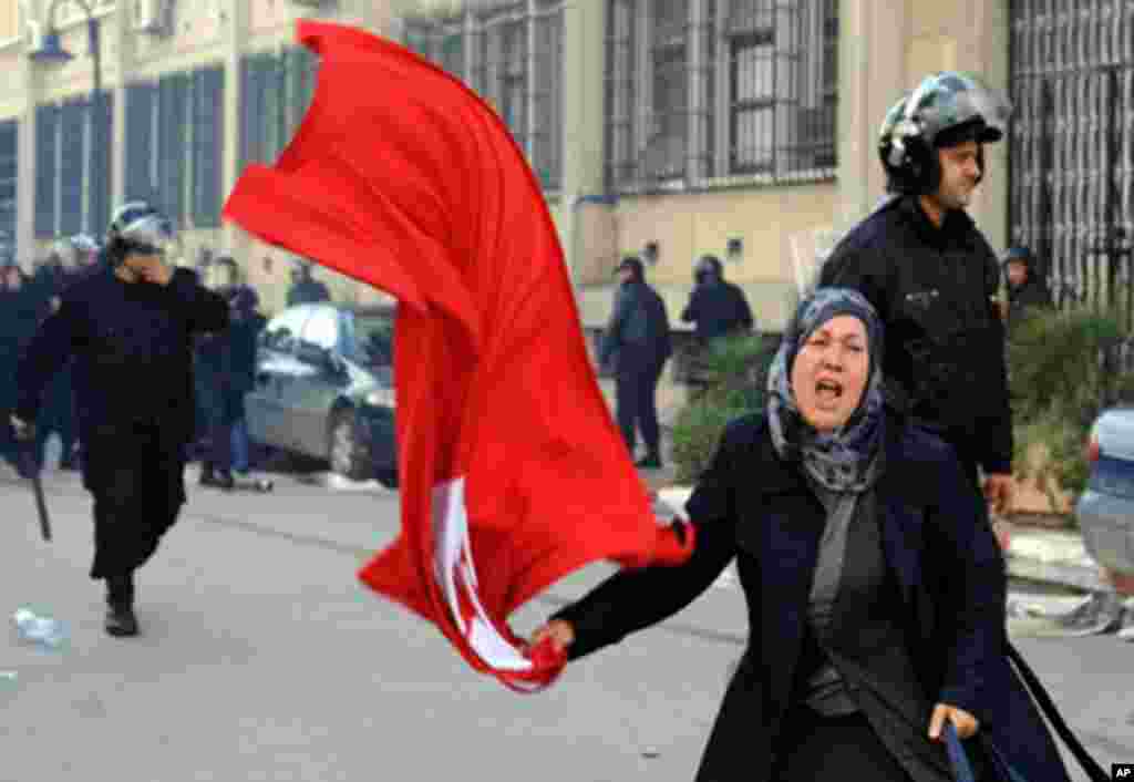 A Tunisian woman waves the national flag in front of the interior ministry during clashes between demonstrators and security forces in Tunis, 14 Jan 2011. Thousands of Tunisians demanded the departure of President Zine El Abidine Ben Ali in marches in the