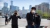 People wear face masks to protect against the spread of the new coronavirus as they wait to cross an intersection in Beijing, April 23, 2020.