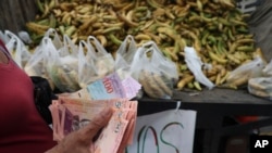 En esta foto del 8 de mayo de 2019, una mujer cuenta sus bolívares -la moneda venezolana- antes de comprar una bolsa de plátanos en el área de Petare de Caracas, Venezuela.