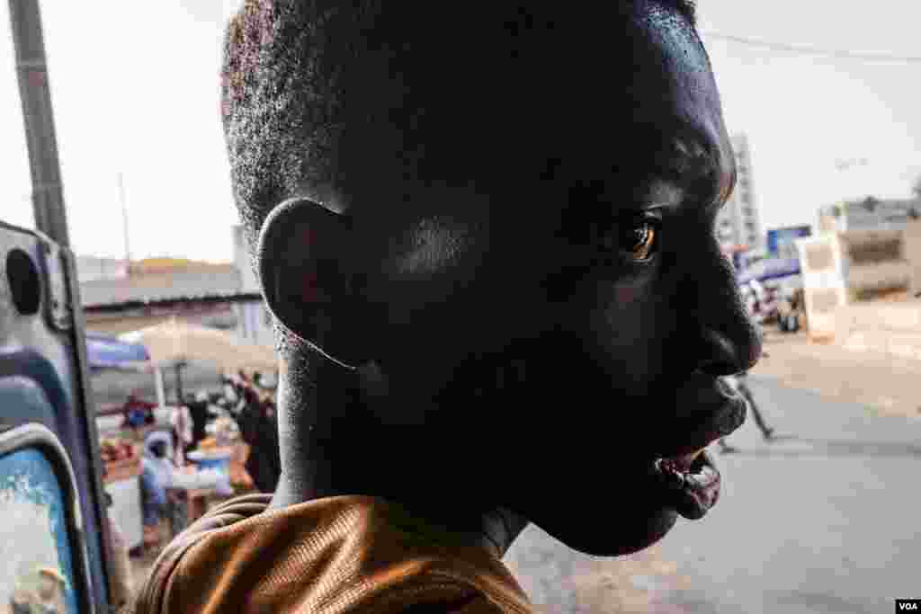 An apprentice hangs off the back of a minibus, directing passengers and taking payments for rides. (R. Shryock/VOA)