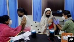 Health workers administer COVID-19 vaccine to women at a vaccination center in Mumbai, India, Friday, Jan. 7, 2022. 