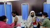 Health workers administer COVID-19 vaccine to women at a vaccination center in Mumbai, India, Friday, Jan. 7, 2022. 