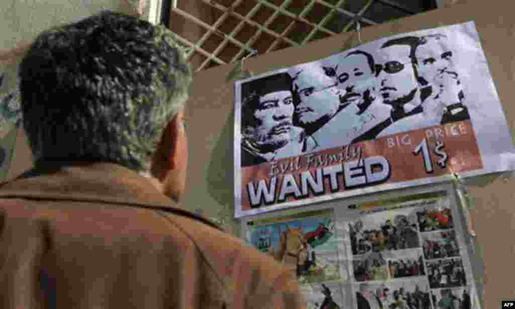 A Libyan man inspects an anti-Gadhafi poster hanging in the street during the ongoing protest at the Tahrir square in Benghazi, Libya Saturday, March 12, 2011. Moammar Gadhafi tightened his grip Saturday on the coastal road linking his territory to the r