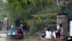 Anak-anak sekolah dan warga menggunakan perahu kecil untuk belewati jalanan di distrik Quang Dien, provinsi Thua Thien Hue, Vietnam Tengah yang tergenang banjir (18/11).