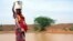 A woman gets water from a pool infected with cholera in Gounfara, Niger, despite warnings from medical services, August 29, 2005.