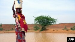 A woman gets water from a pool infected with cholera in Gounfara, Niger, despite warnings from medical services, August 29, 2005.