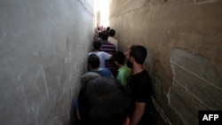 FILE - Syrians line up to buy bread at a shop in the town of Binnish in the country's northwestern Idlib province, June 9, 2020. 