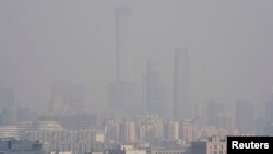 The Beijing skyline is seen in smog ahead of Chinese Lunar New Year, Feb. 13, 2018. A slight slowing in the Chinese economy is linked to the new year holiday and stricter pollution measures.