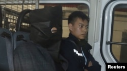 Shi Deyun (kiri) duduk di sebelah polisi setibanya di pengadilan Hong Kong, China (25/1).