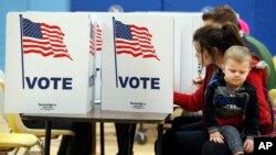 A woman holds her son as she fills out her ballot at a polling place Nov. 7, 2017, in Alexandria, Va.