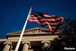 Bendera Amerika berkibar di luar Gedung Departemen Kehakiman AS di Washington, AS, 15 Desember 2020. (Foto: REUTERS/Al Drago)