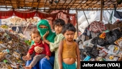 A Rohingya woman has her children with her at her workplace at a Rohingya refugee camp in Faridabad, India, in April 2024. Most Rohingya refugees do menial jobs such as rag picking for a living in India.