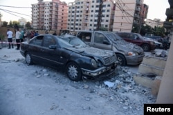 Ljudi stoje u blizini oštećenih vozila na mestu pogođenom u izraelskom napadu u kom je, prema bezbednosnom izvoru, ubijen lider Hamasa Said Atal i tri člana njegove porodice, u severnom gradu Tripoliju, u Libanu, 5. oktobra 2024.