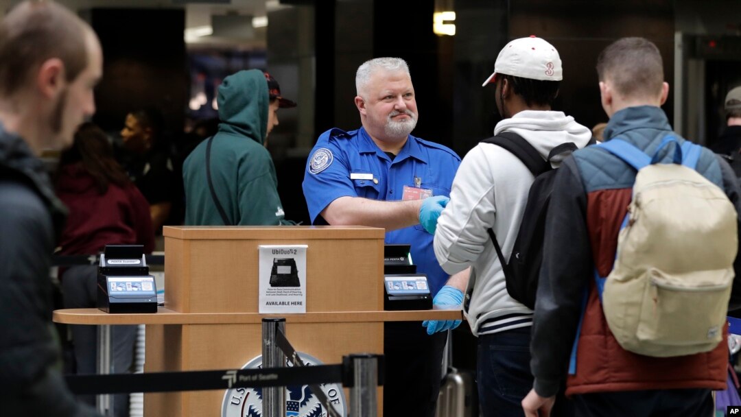 Seorang pekerja keamanan bandara menyerahkan kartu identitas kepada calon penumpang di Bandara Internasional Seattle-Tacoma di Seattle, 25 Januari 2019. 