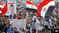 Supporters of Muslim brotherhood's presidential candidate Mohamed Morsi wave Egypt's national flag and posters of him in Tahrir Square in Cairo, June 19, 2012.