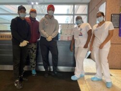 In this April 10, 2020, handout photo, Japneet Singh, center, and two other volunteers deliver pizza to health care workers at Kings County Hospital in the Brooklyn borough of New York.