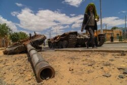 A man passes by a destroyed tank on the main street of Edaga Hamus, in the Tigray region, in Ethiopia, on June 5, 2021. (Yan Boechat/VOA)