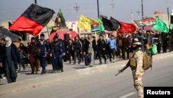 An Iraqi soldier stands guard as Shi'ite pilgrims walk to the holy city of Kerbala, ahead of the religious ceremony of Arbain, in Baghdad, Dec. 21, 2013. 