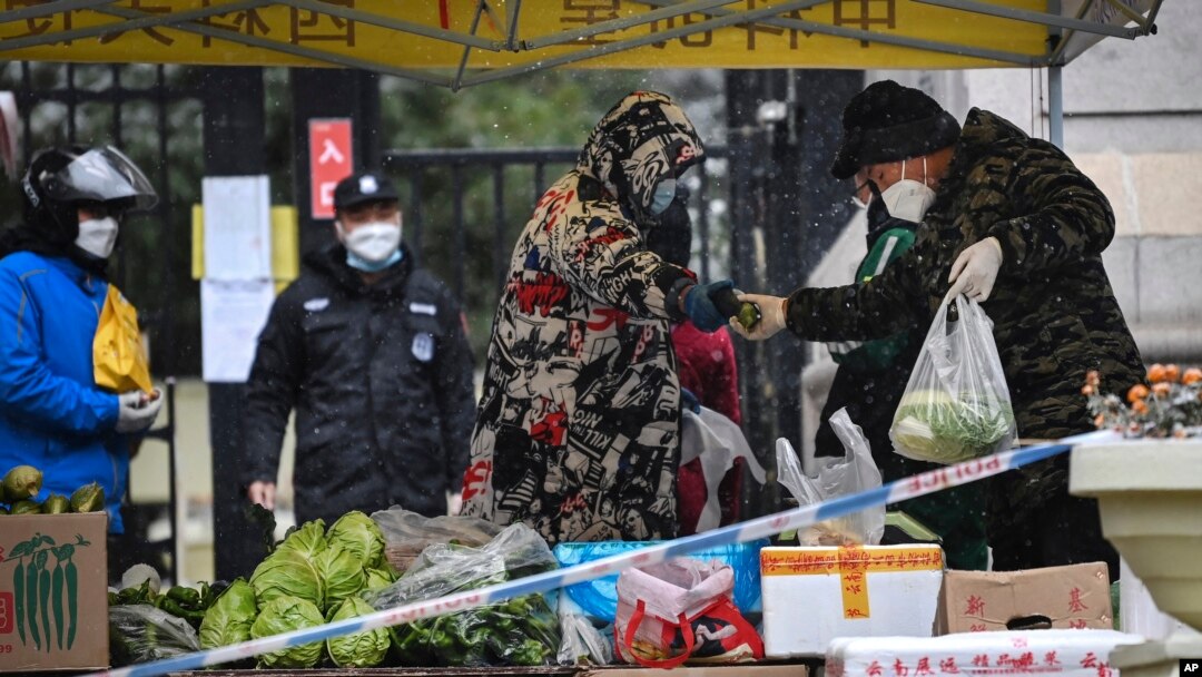 Para warga membeli kebutuhan pokok dari pasar sementara yang digelar di depan area karantina di Xi'an, provinsi Shaanxi, China, pada 25 Desember 2021. (Foto: Xinhua via AP/Tao Ming)