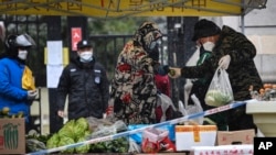 Para warga membeli kebutuhan pokok dari pasar sementara yang digelar di depan area karantina di Xi'an, provinsi Shaanxi, China, pada 25 Desember 2021. (Foto: Xinhua via AP/Tao Ming)