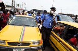 FILE - Lagos Commissioner of Police, Hakeem Odumosu (C), squeezes his way through a crowded market to monitor compliance measures to curb the spread of the COVID-19 coronavirus at the Mile 12 Market in Lagos, Nigeria, March 26, 2020.