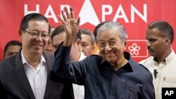 Malaysia's Prime Minister Mahathir Mohamad, center, waves next to newly appointed Finance Minister Lim Guan Eng, left, after a press conference to announce his cabinet members in Petaling Jaya, May 12, 2018. 