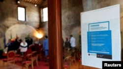 A health advisory poster is seen during a wedding ceremony with limited number of guests, standing one meter away from each other, as Italy struggles to combat a coronavirus outbreak, at the Caracalla wedding venue in Rome, Italy March 7, 2020.