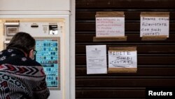 Un hombre con una máscara sanitaria compra cigarrillos en un dispensador, cerca de una tienda de tabaco en Codogno, Italia, una de las ciudades cerradas debido al coronavirus. Foto: Marzio Toniolo. Marzo 1, 2020.