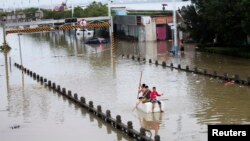 Residents paddle a makeshift raft as they make their way along a flooded street after Typhoon Fitow hit Rui'an, Oct. 7, 2013. 