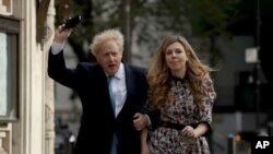 El primer ministro británico, Boris Johnson, llega a un colegio electoral con su cónyuge Carrie Symonds para emitir su voto en las elecciones del consejo local, en Londres , el 6 de mayo de 2021.