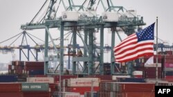 FILE - Chinese shipping containers are stored beside a U.S. flag after they were unloaded at the Port of Los Angeles in Long Beach, California, May 14, 2019. 