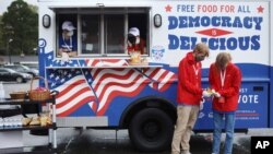 Sejumlah anak muda membagikan makanan dan minuman gratis untuk para pemilih yang mengantre di tempat-tempat pemungutan suara di Charlotte, North Carolina, 29 Oktober 2020. (Foto: AP/Travis Dove)