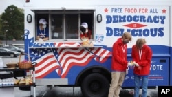 Young people are joining the efforts to deliver free food and drink to voters waiting in long lines at the polls, Oct. 29, 2020 in Charlotte, N.C. 