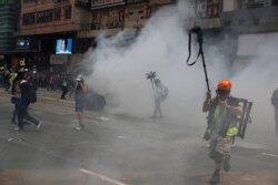 FILE - Journalists make their way through tear gas in Hong Kong, Sept. 29, 2019.