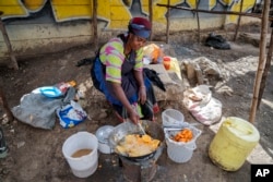 A woman fries potatoes in the low-income Kibera neighborhood of Nairobi, Kenya, Tuesday, April 19, 2022. (AP Photo/Khalil Senosi)