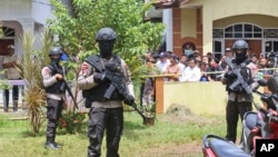 Police officers stand guard at a residential neighborhood where police conducted a raid on a house used by suspected militants, in Tangerang, Indonesia, Dec. 21, 2016.