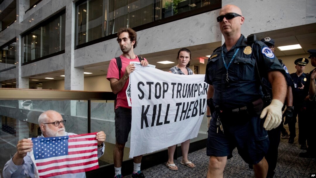 Polisi Capitol Hill berjalan di depan kelompok pengunjuk rasa yang memprotes RUU layanan kesehatan Partai Republik di Washington.