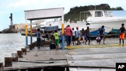 Masyarakat sedang menyelamatkan bagian-bagian dari pelabuhan yang rusak dihantam Badai Irma di Antigua dan Barbuda, 6 September 2017. 