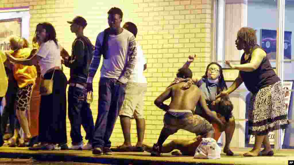 Des personnes viennent en aide à une femme en détresse après des coups de feu tirés après une manifestation à Ferguson, Missouri, 9 août 2015. &nbsp;